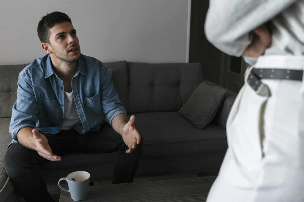 Uomo che parla con donna in soggiorno, discussione animata.