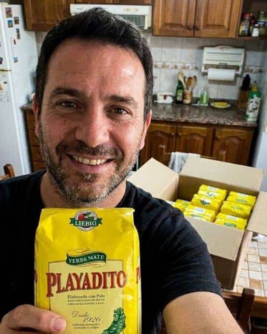 Uomo felice con confezione di Yerba Mate Playadito in cucina.