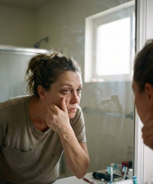 Donna triste si guarda allo specchio, riflettendo sulla sua immagine.