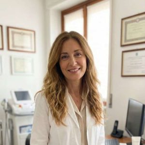 Donna sorridente in ufficio con certificazioni e computer.