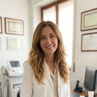 Donna sorridente in ufficio con certificazioni e computer.