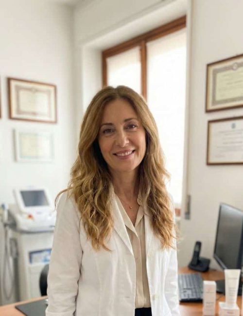 Donna sorridente in ufficio con certificazioni e computer.